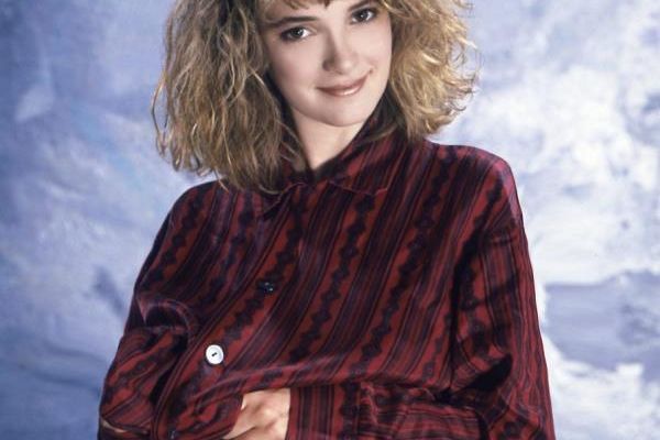 1986 portrait of actress Winona Ryder with curly hair, wearing a red shirt in Los Angeles, California